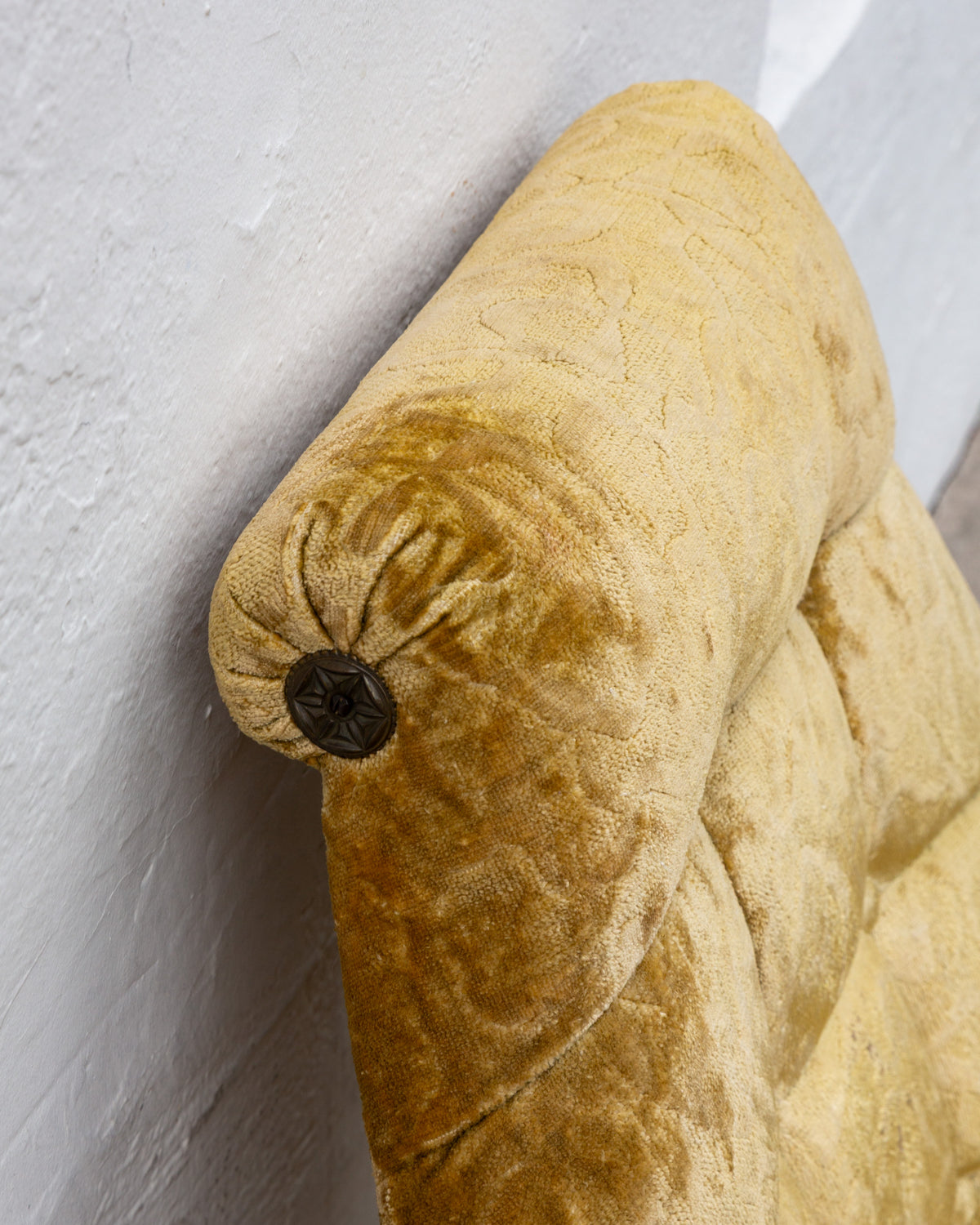 Detail of the rolled headrest end capped with a carved dark wood rosette button