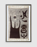 Straight-on view of a framed woven wool tapestry with abstract figures in dark brown on gray, cream fringe top and bottom, in a black and gold frame, on a light gray background.
