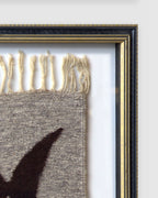 Upper right corner of the black and gold frame, with the tapestry fringe and white mat behind glass, on a light gray background.