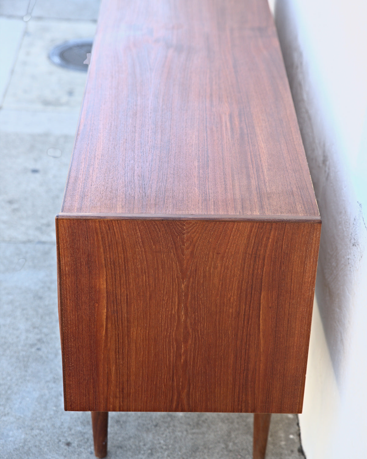 End view of a Danish teak credenza showing the top grain running its full length