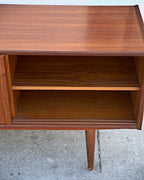 Teak credenza with a door slid open to show an adjustable shelf inside