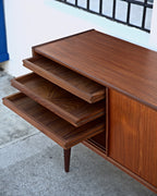 Three teak trays pulled out in steps from the end section of a Danish credenza