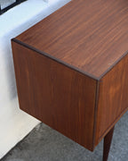 Top corner of a Danish teak credenza with a dark edge band and straight teak grain