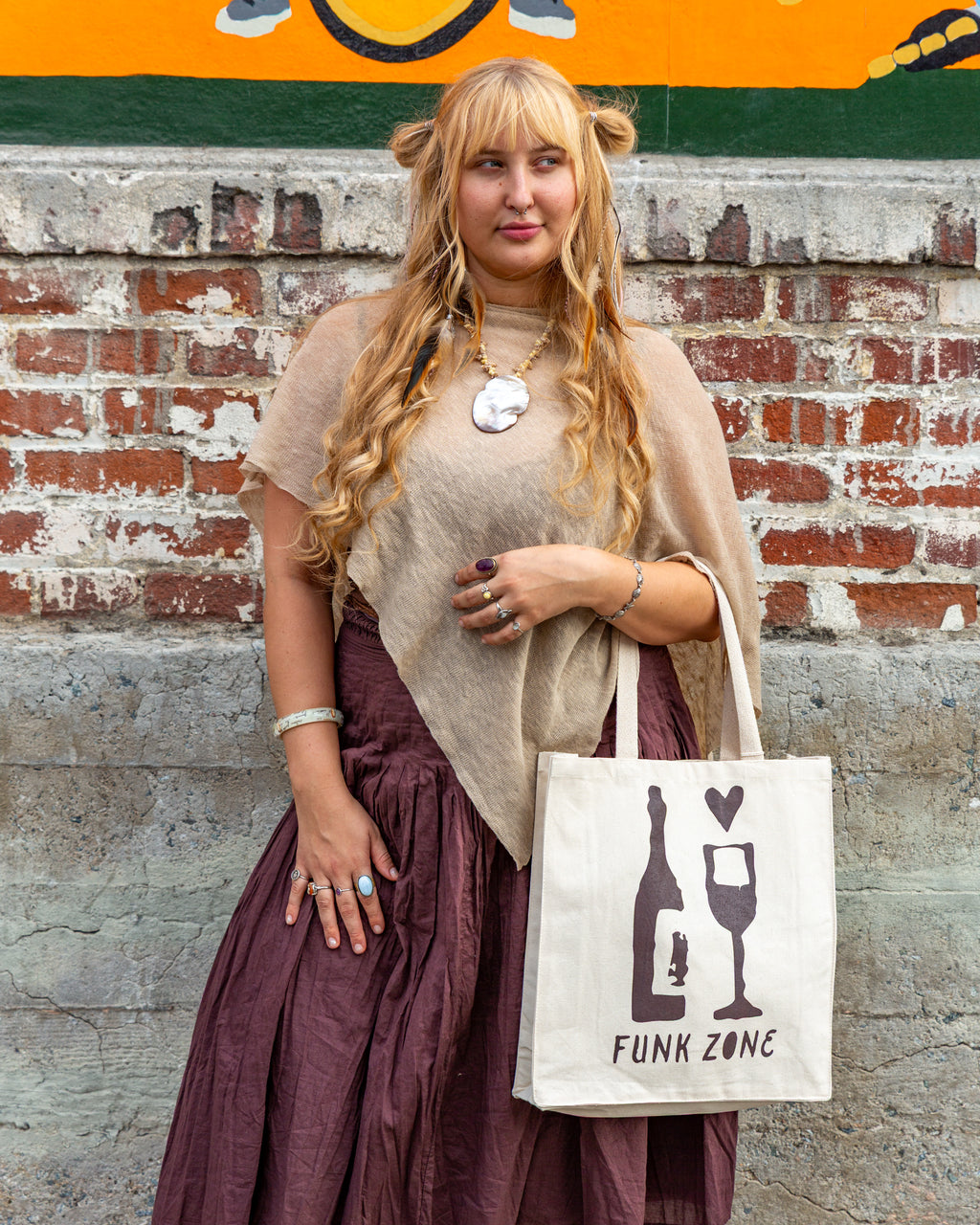 The Funk Zone canvas tote worn on the shoulder in front of a painted brick wall in the Santa Barbara Funk Zone.