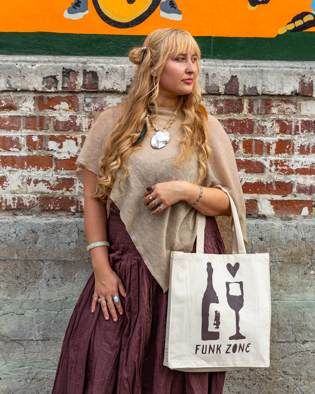 Full length view of the natural canvas Funk Zone tote hanging at the hip, showing the bag's depth and long cotton handles.