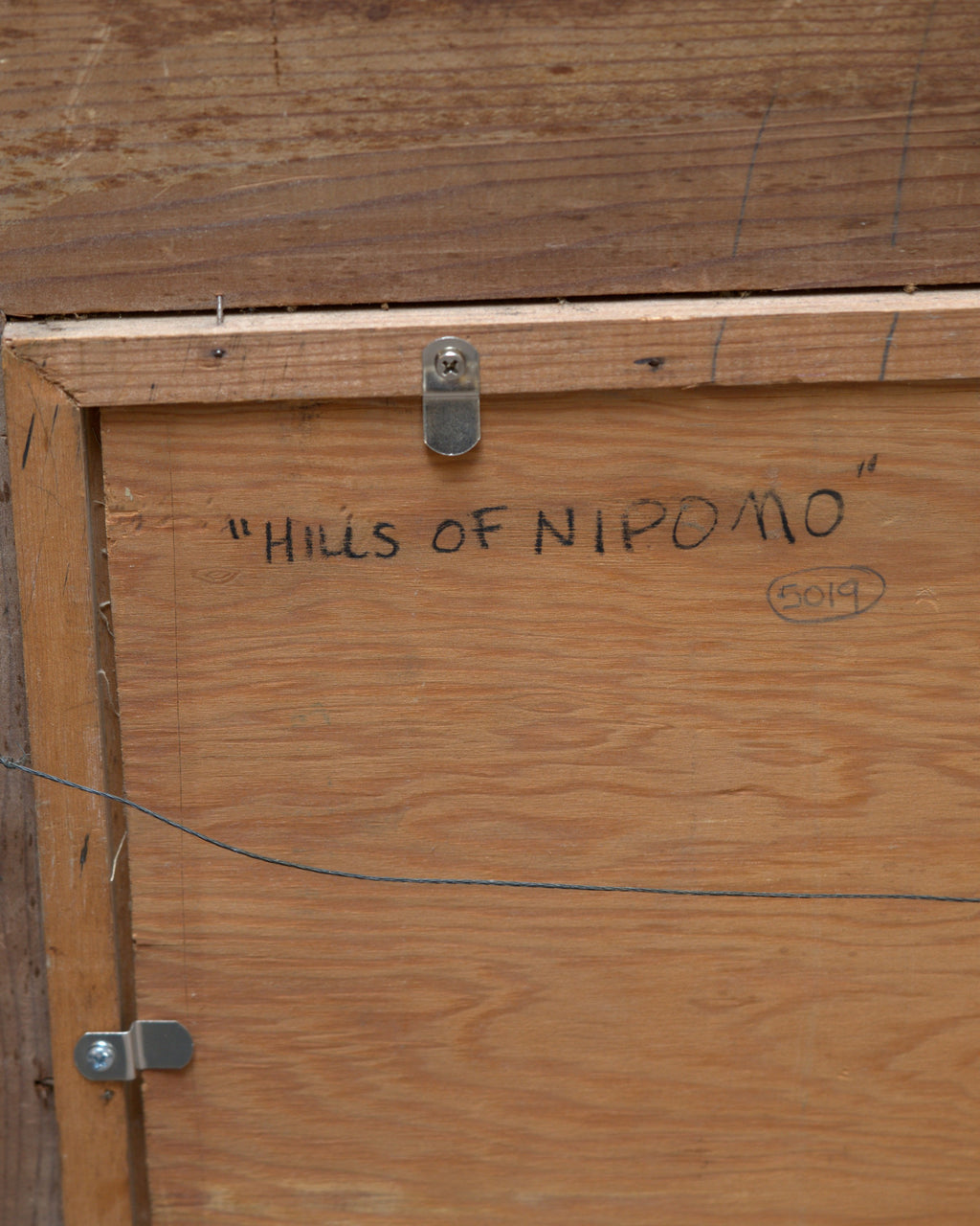 Back of the Milford Zornes painting Hills of Nipomo, with the title written in marker on the backing board.